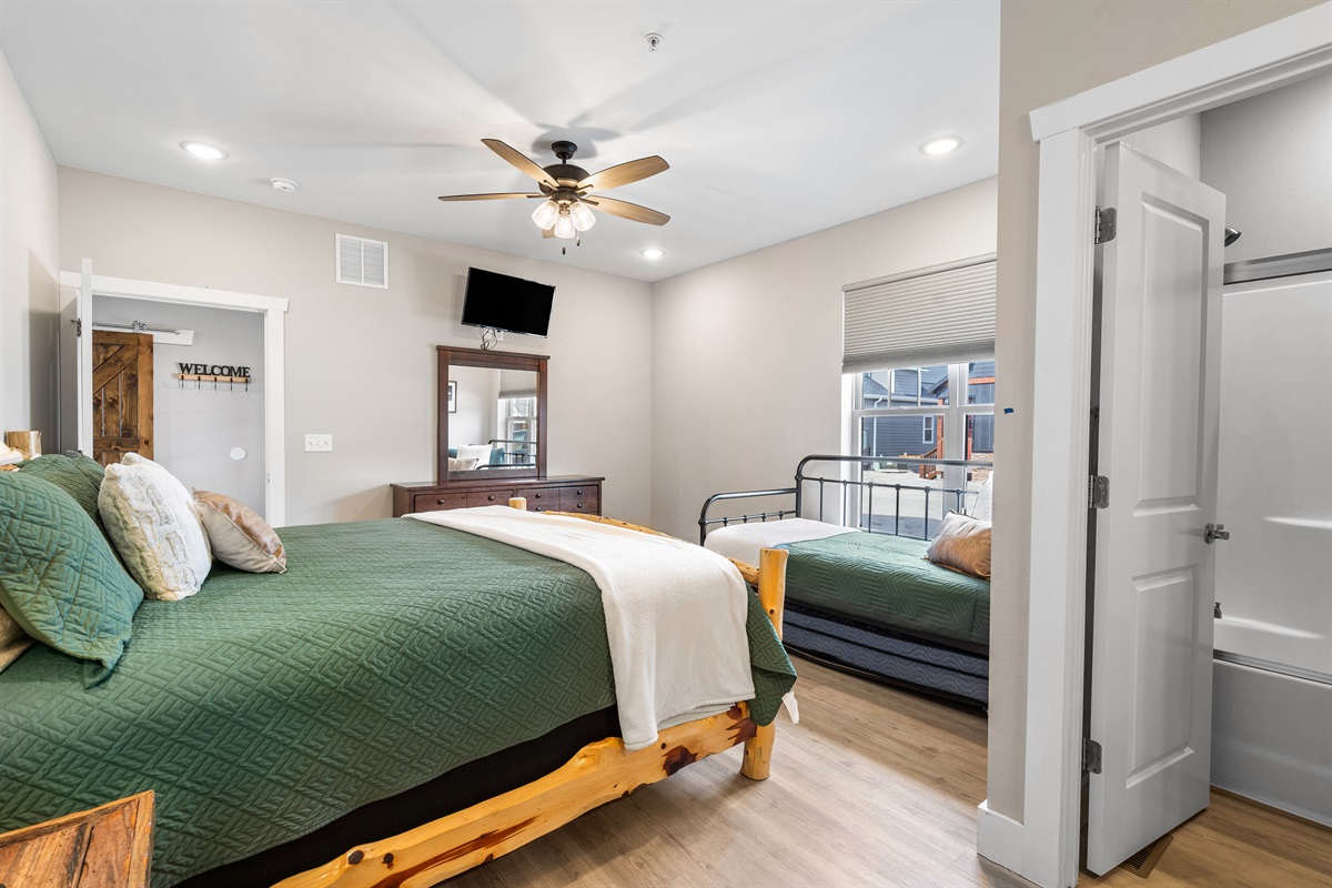 Main Level Bedroom #2 featuring a king bed, twin trundle bed, and private en-suite bathroom with tub/shower — perfect for families or extra guests.