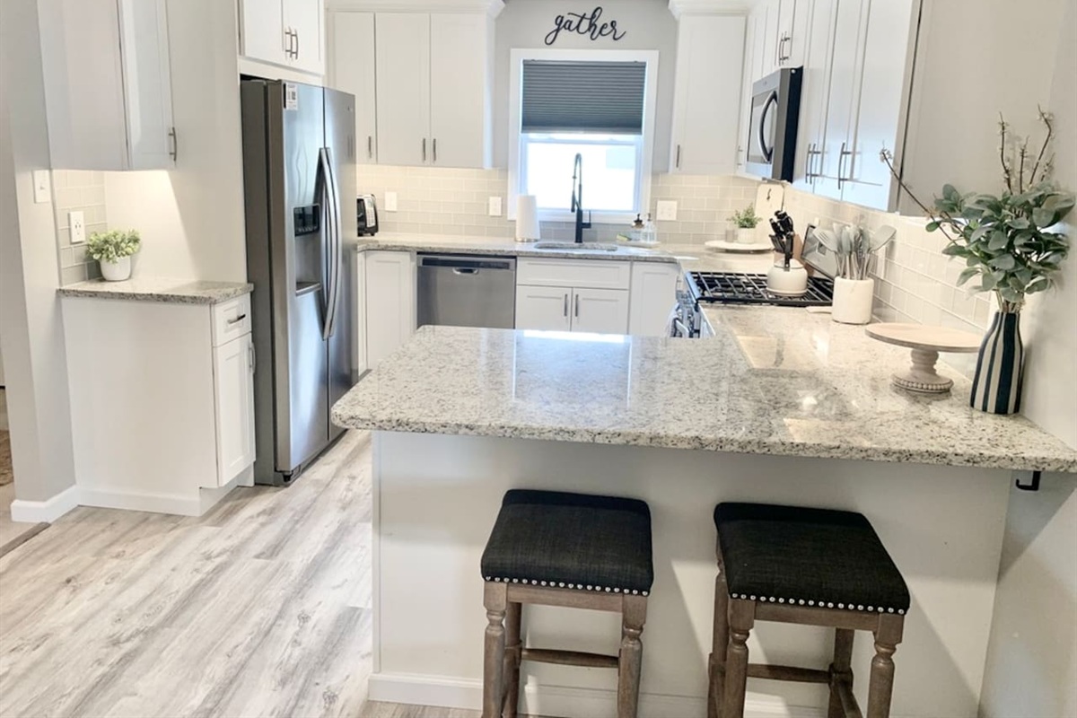 Cook with style in this bright, updated kitchen featuring stainless steel appliances and white cabinetry. The expansive granite countertops and breakfast bar seating make it a perfect spot for morning coffee or casual meal prep.