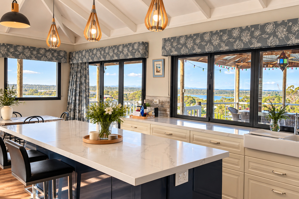 The kitchen opens through wide bifold windows onto the covered deck, with a large island bench, a farmhouse sink and views across Preston Beach to Lake Preston and Yalgorup National Park.