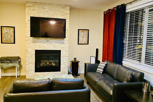 Stylish living room with stone fireplace, leather sofas & smart TV.