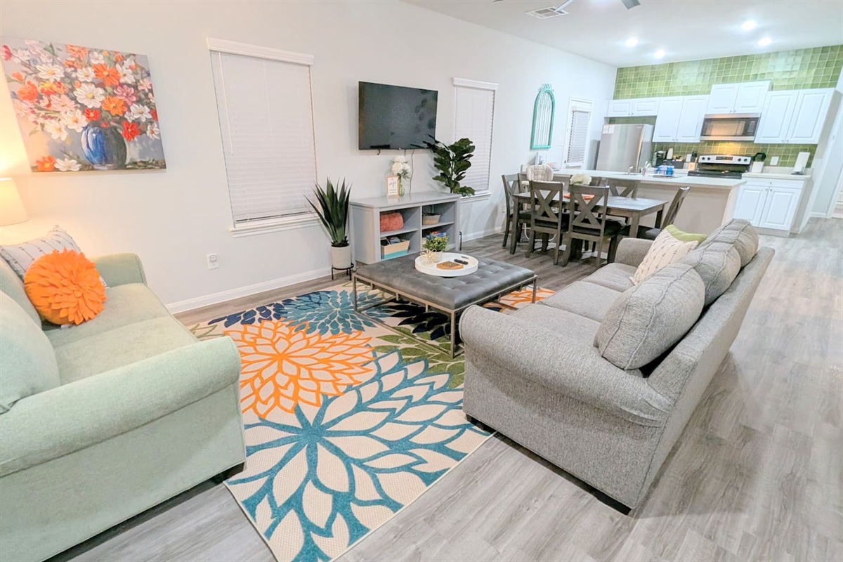 Cozy living room with two couches, ottoman, and open concept access to the dining area. Relax while watching the Roku smart TV or play some board games with the family. 
