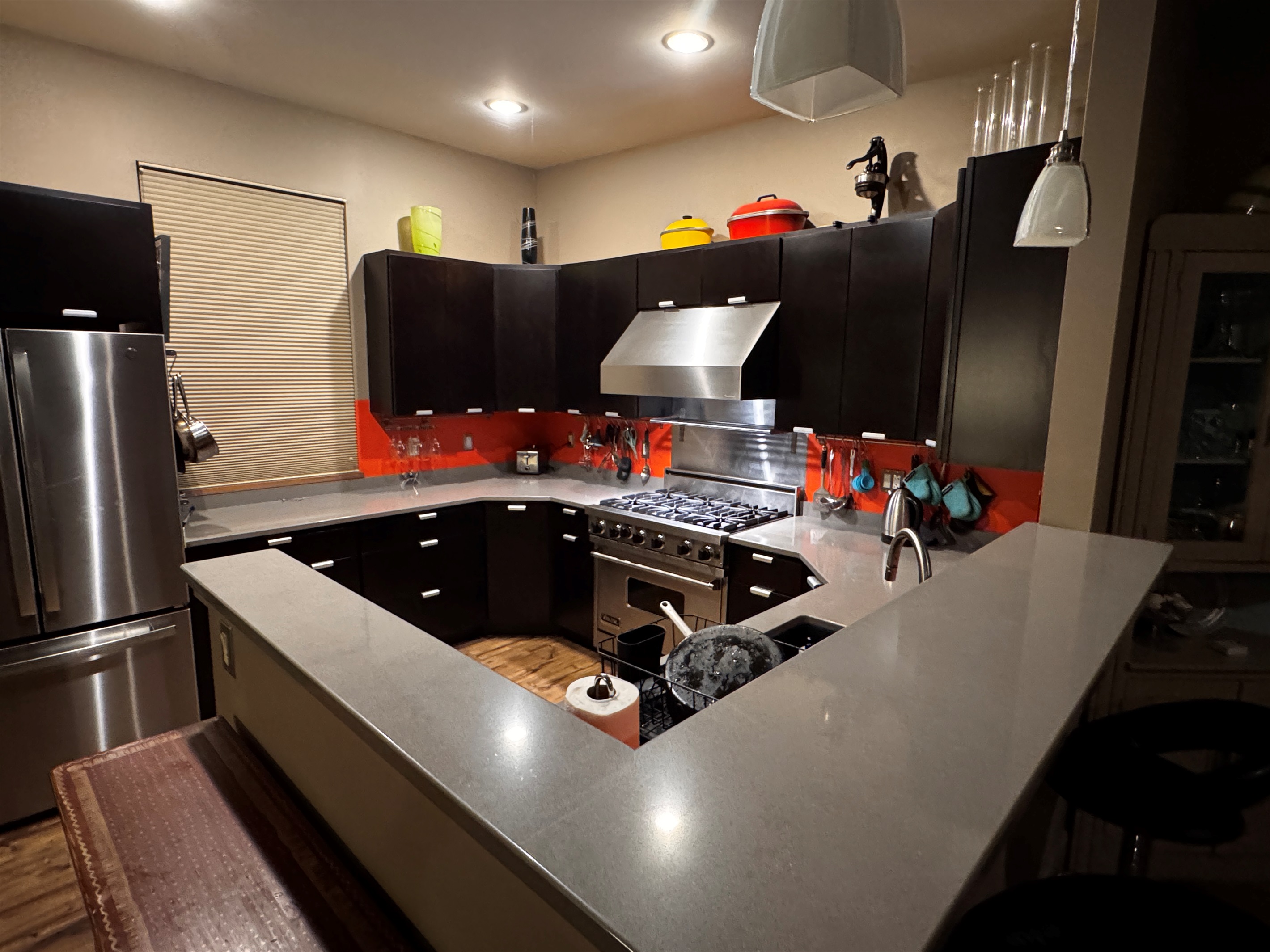 Open-concept main floor looking over the breakfast bar toward the chef’s kitchen and dining area. This central hub connects the living spaces to the staircase, providing a seamless flow for groups staying at our Mount Desert Island retreat.