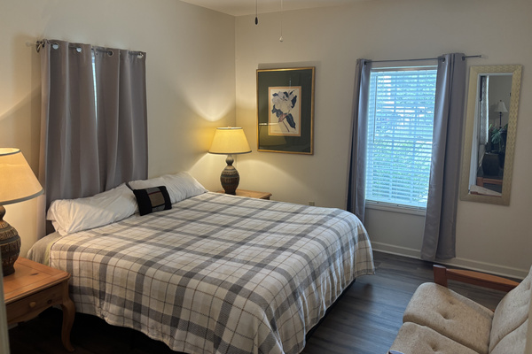 Spacious primary suite with a king bed, blackout curtains, comfortable sitting area and private en-suite bathroom.