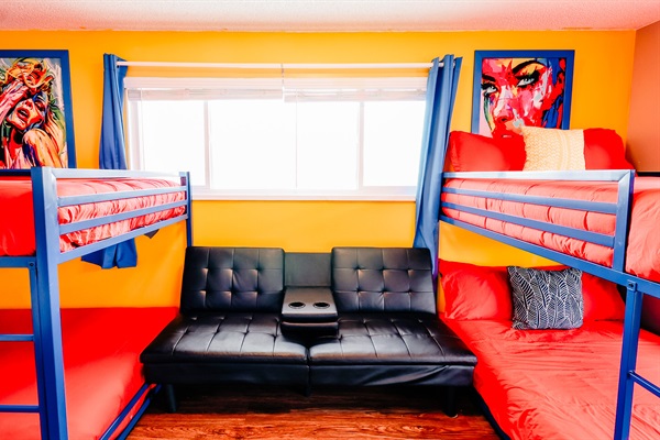 Playful Slumber: Double Bunk Beds in Cheerful Blue Frames, Complemented by Vibrant Red-Orange Covers, Against a Backdrop of Soothing Yellow Walls. Relax in Style with Theater-inspired Chairs 🌟🛌