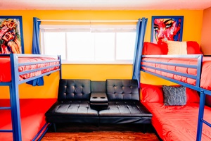 Playful Slumber: Double Bunk Beds in Cheerful Blue Frames, Complemented by Vibrant Red-Orange Covers, Against a Backdrop of Soothing Yellow Walls. Relax in Style with Theater-inspired Chairs 🌟🛌
