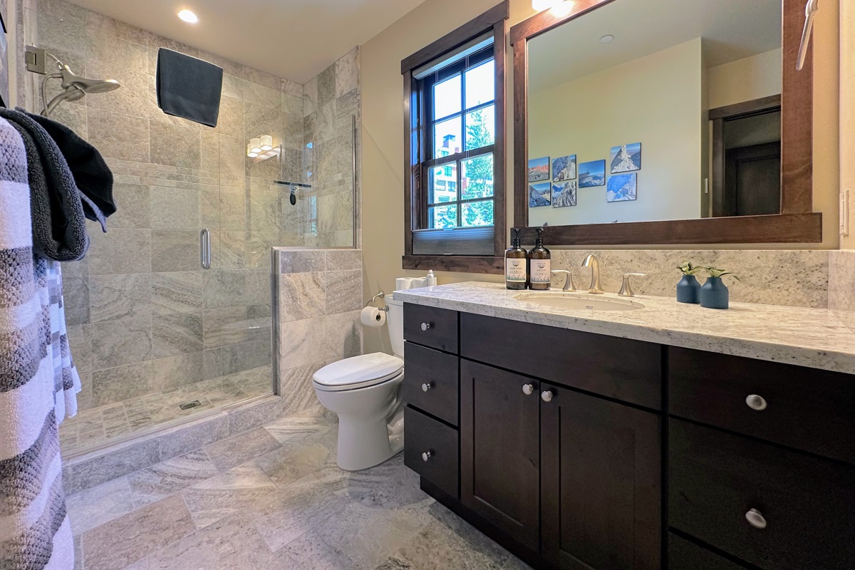 The second primary bath features a sleek walk-in shower and smart design touches—proving that functionality doesn’t have to sacrifice style.