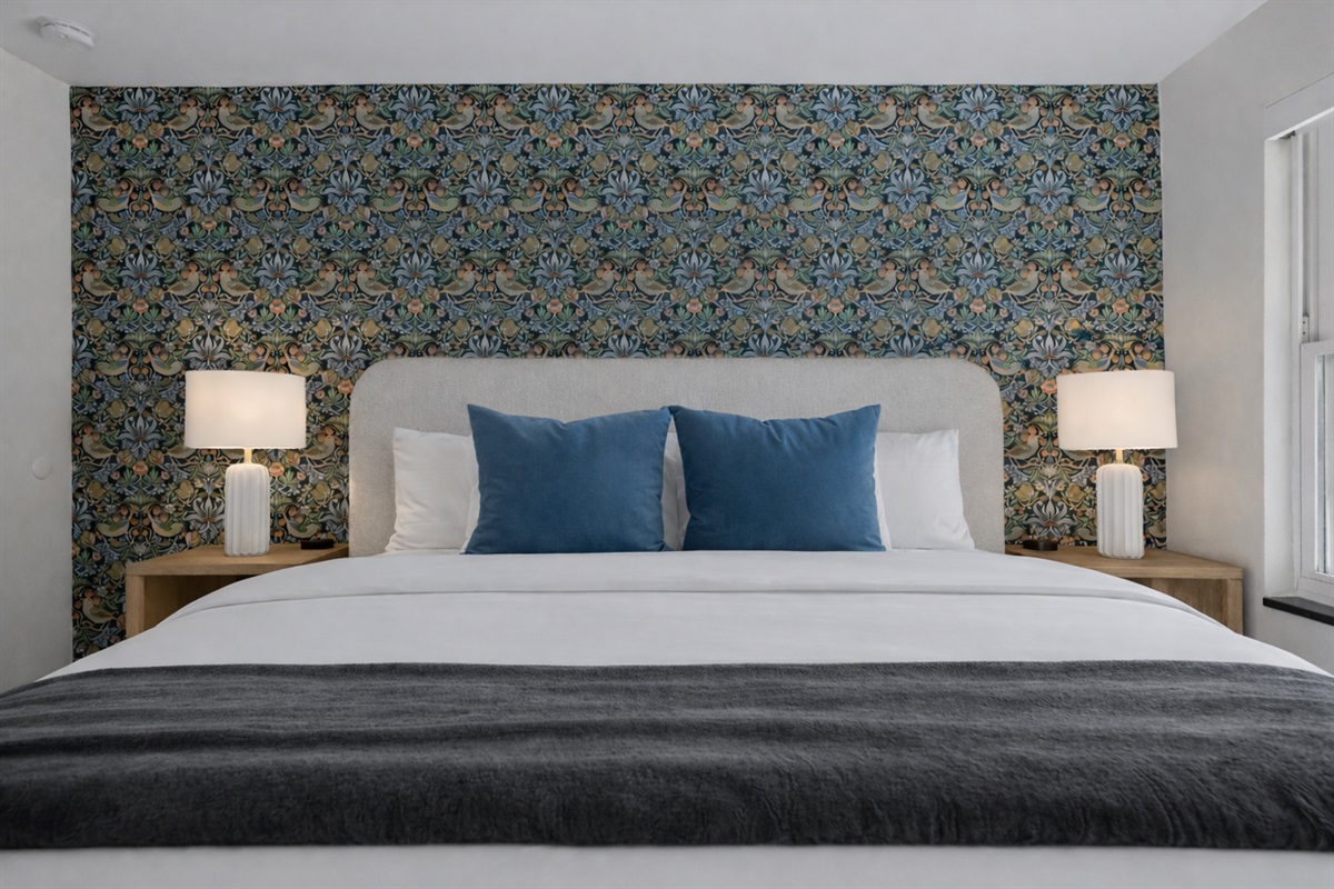 Stylish bedroom retreat with a plush bed, bold accent wall, soft lighting, and hotel-quality comfort for a truly relaxing stay.