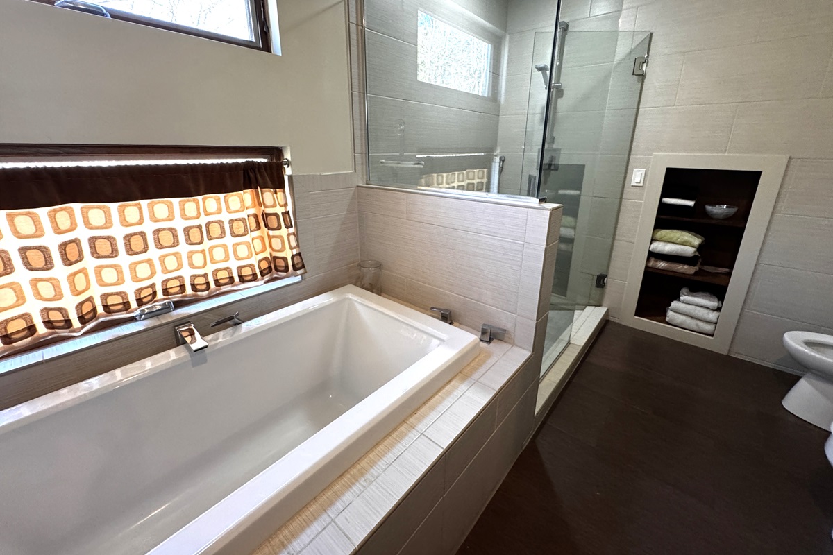 Spa-like primary ensuite featuring a deep soaking tub and a modern glass-enclosed shower. Bathed in natural light with the added comfort of a heat lamp, this private retreat is the perfect place to recharge after a day of Acadia exploration.