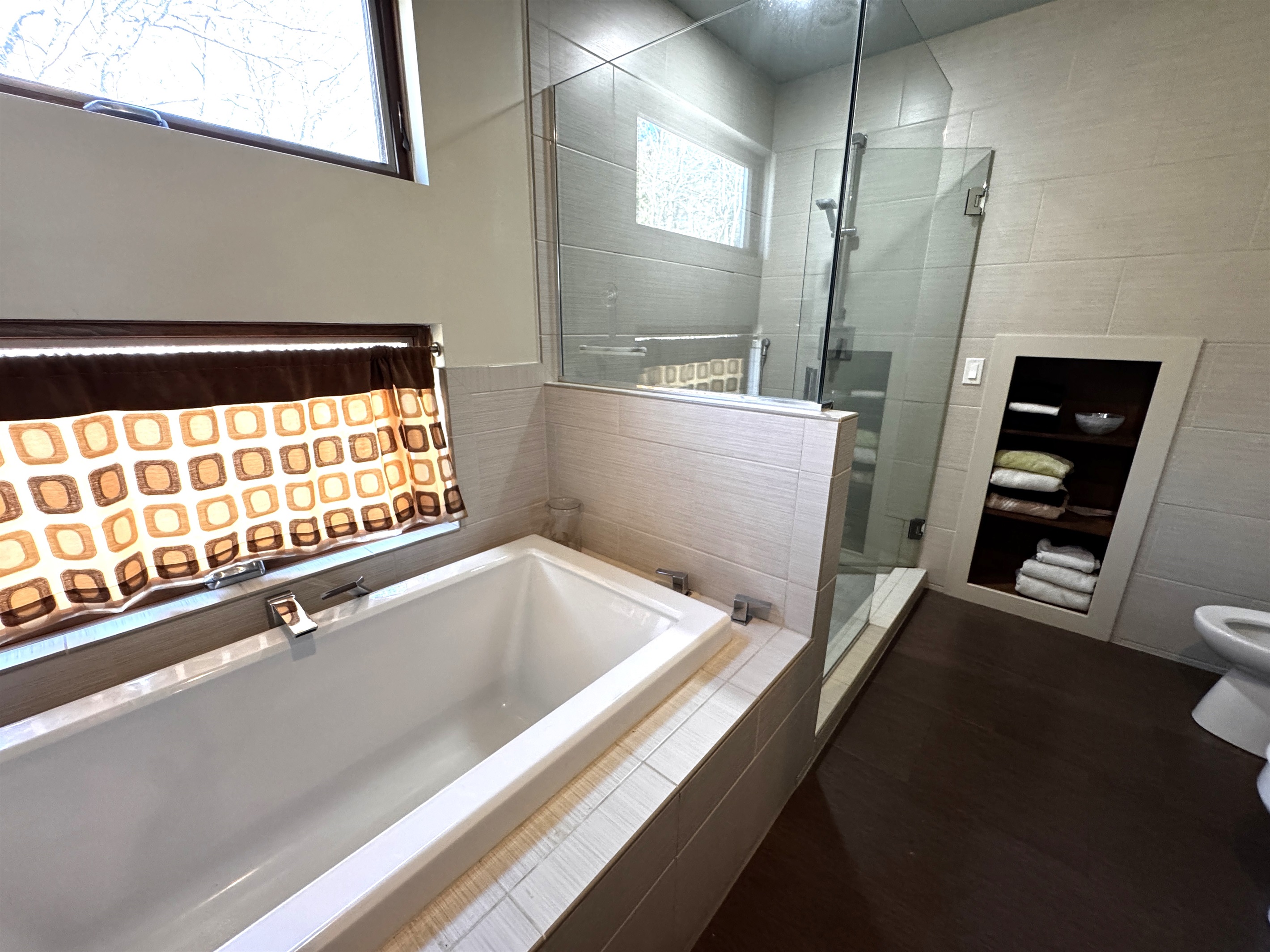 Spa-like primary ensuite featuring a deep soaking tub and a modern glass-enclosed shower. Bathed in natural light with the added comfort of a heat lamp, this private retreat is the perfect place to recharge after a day of Acadia exploration.