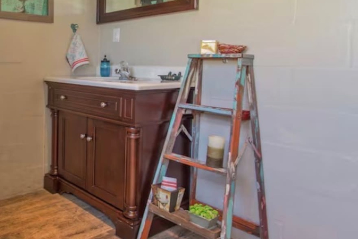 Artist-designed bath with wood vanity, framed mirror, and curated decor. Warm, stylish, and full of character.
