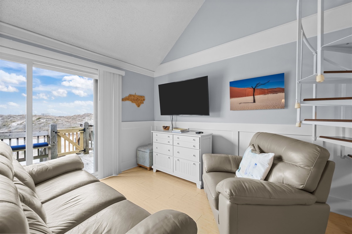 Cozy living room with balcony access&mdash;sink into plush seating and enjoy dune views just beyond the glass