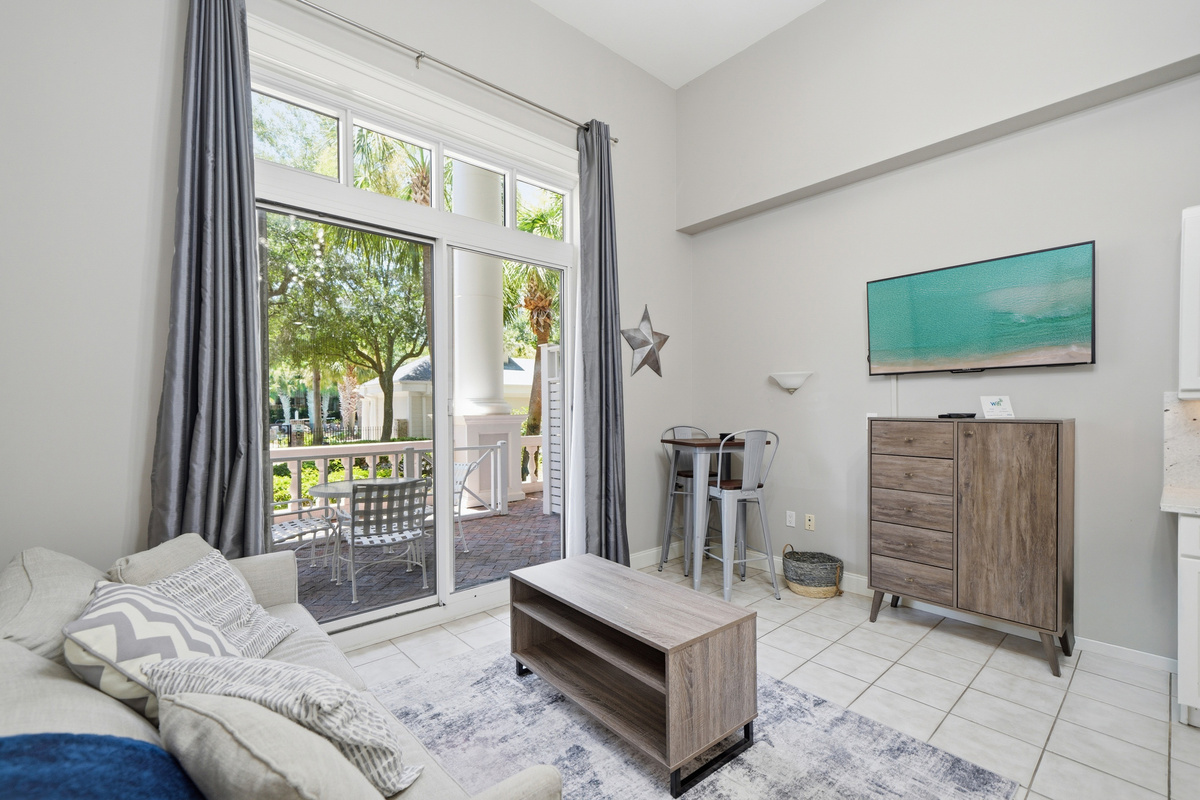 Across from the couch is a mounted flat screen TV, also visible from the bed.