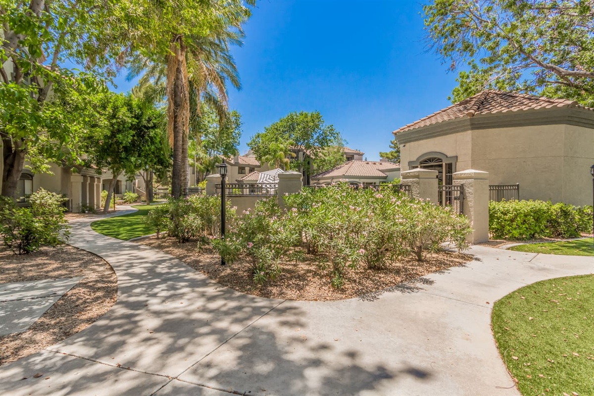 Shared community grounds with shaded walkways, palm trees, and maintained landscaping.