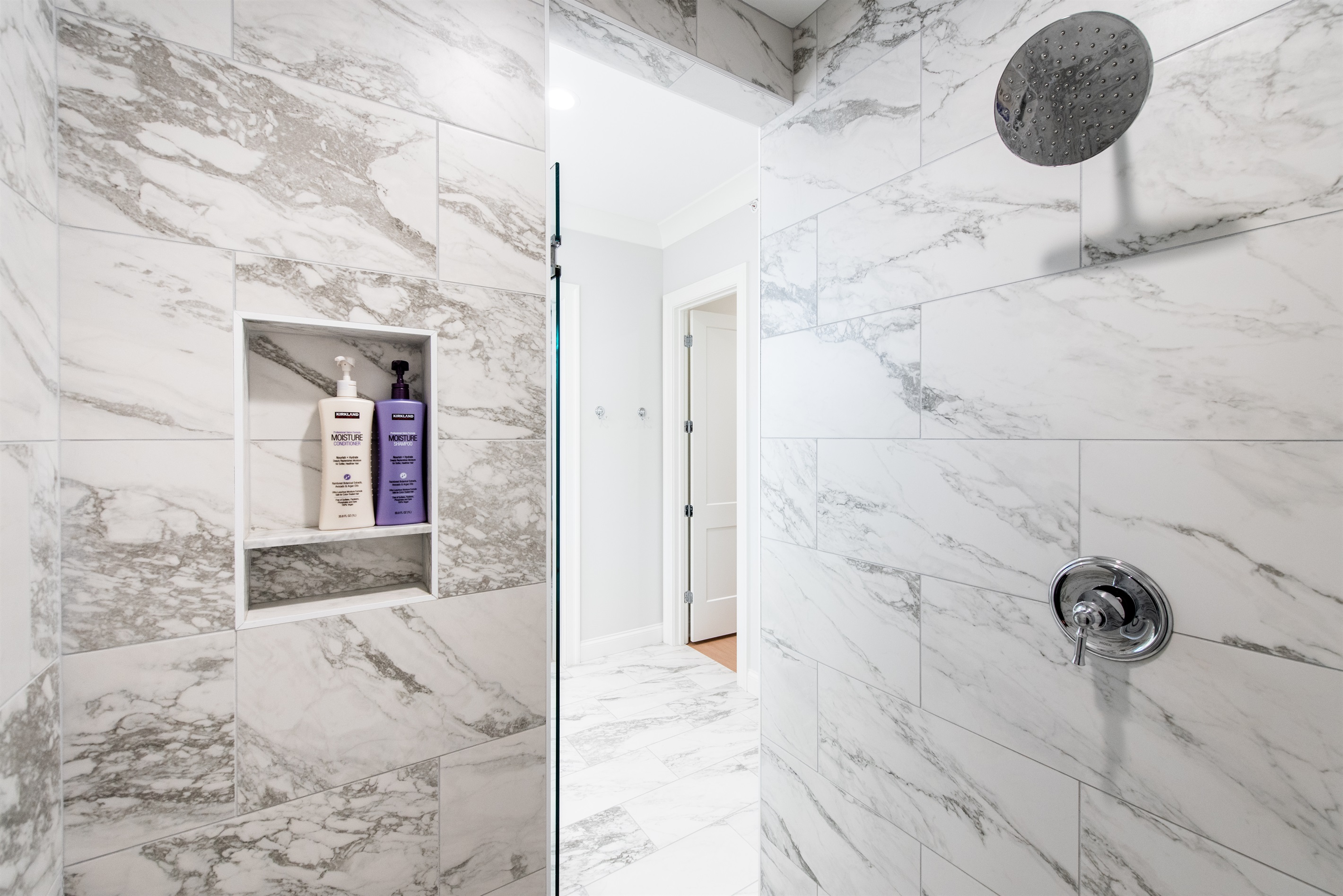 Indulge in a refreshing experience with our modern walk-in shower, featuring elegant marble tiles, a rainfall showerhead, and convenient built-in shelving for your toiletries. Perfect for unwinding after a day exploring the Bourbon Trail.