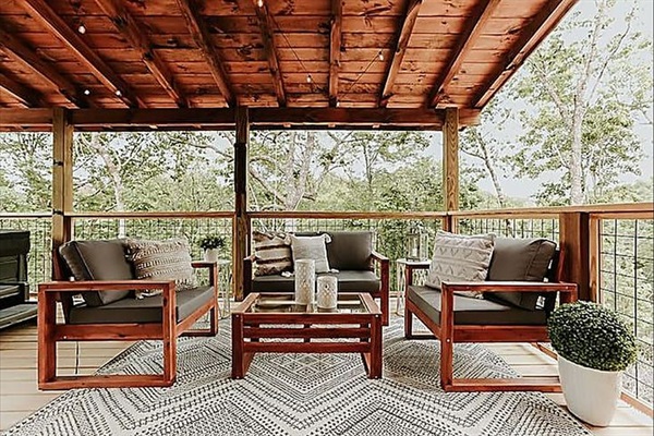 Settle into this dreamy covered deck—complete with comfy seating, string lights, and the calming sounds of the woods
