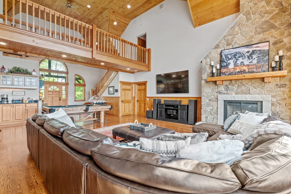 Living room with massive couch, 85" tv, sound system, pool table, and bubble hockey game