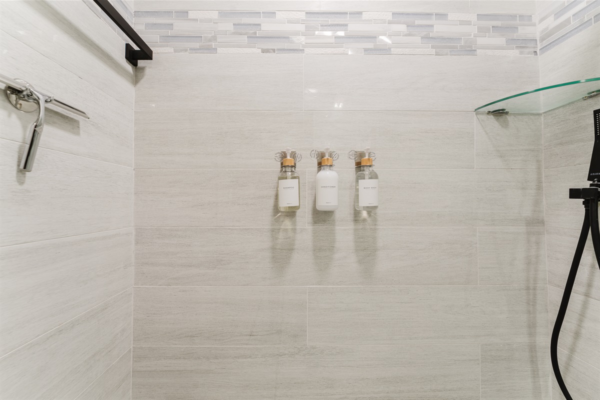 Private spa-style ensuite with a glass-enclosed walk-in shower, marble vanity, matte black fixtures, and hotel-quality finishes.