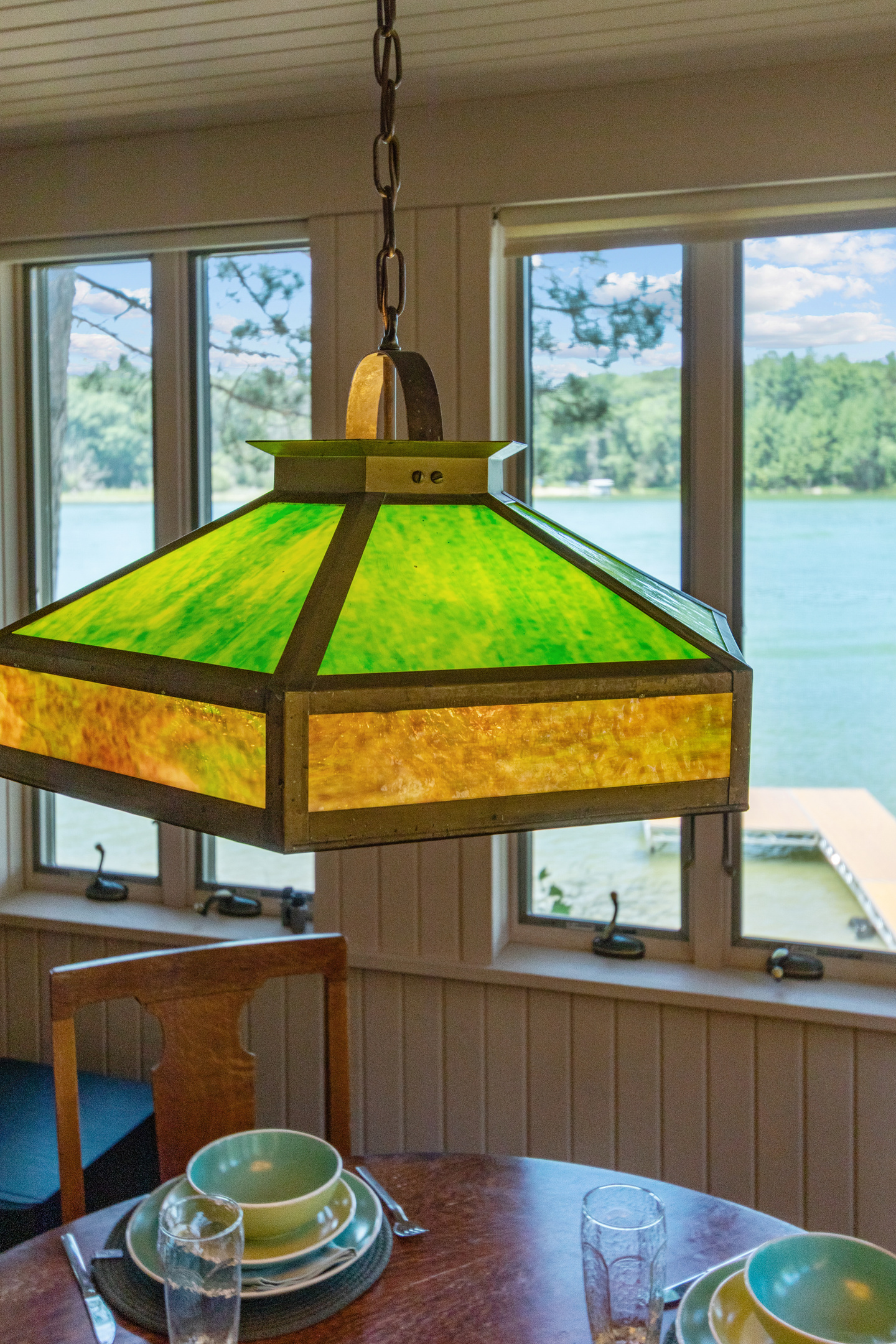 Beautiful cottage charm is in the details, like this one-of-a-kind light casting a warm glow over the table with the lake as your backdrop.