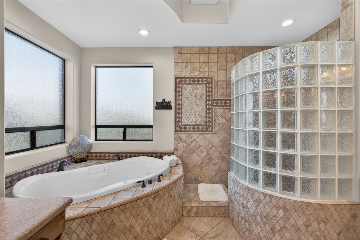 Spa-style primary bathroom with soaking tub and glass-block shower for a true resort-style experience at home