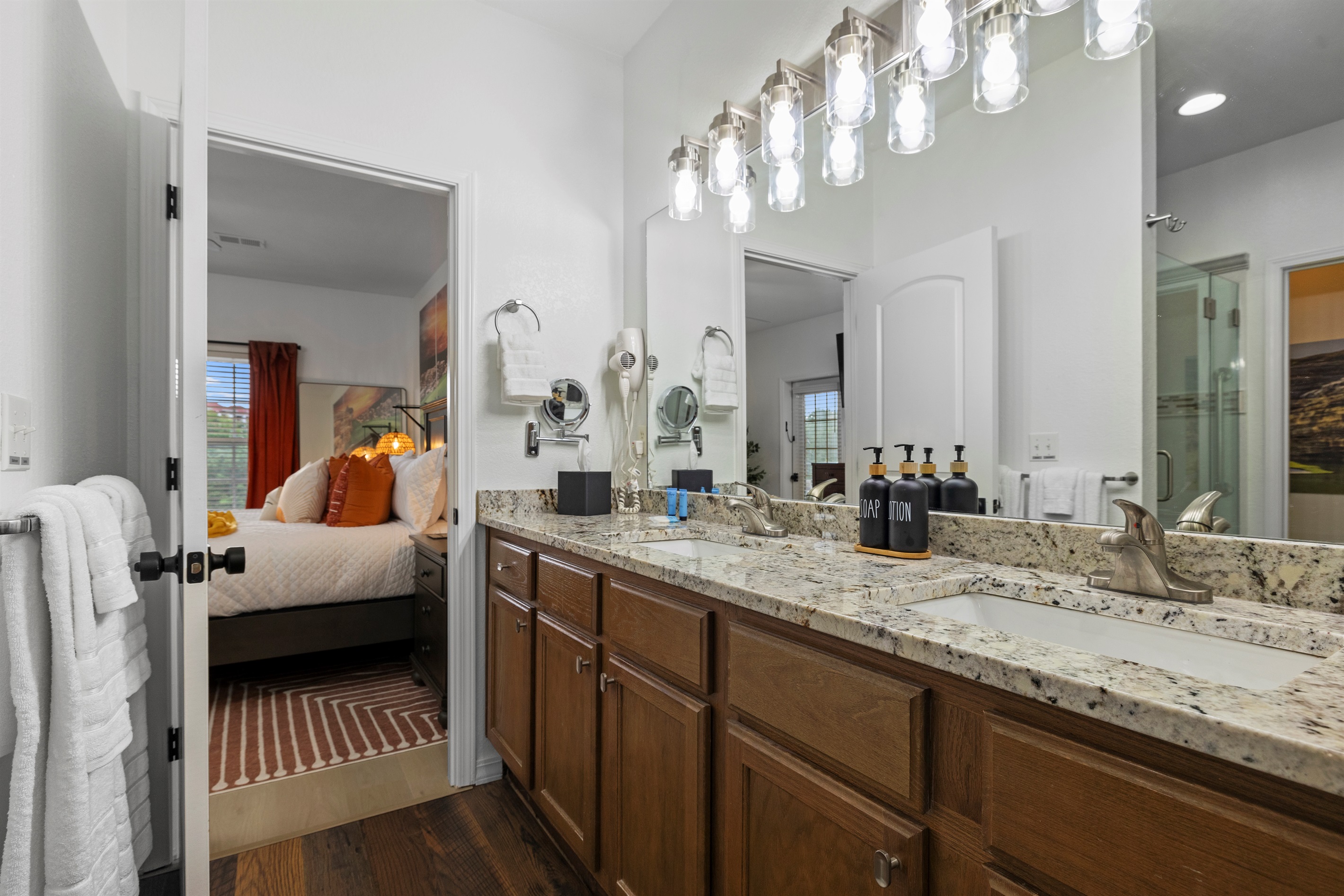 The primary attached ensuite bathroom with double vanity and plenty of lighting