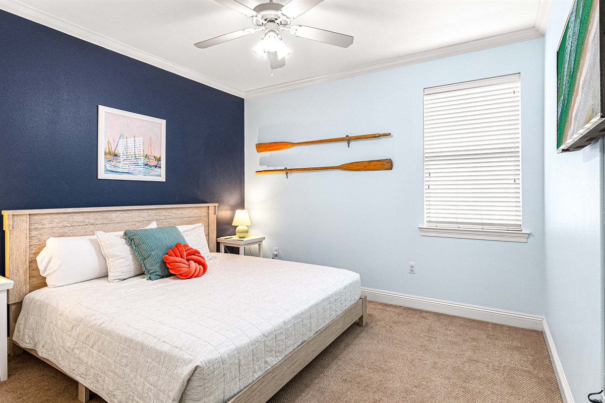 A king bed with coastal vibes and a pop of color to match the view