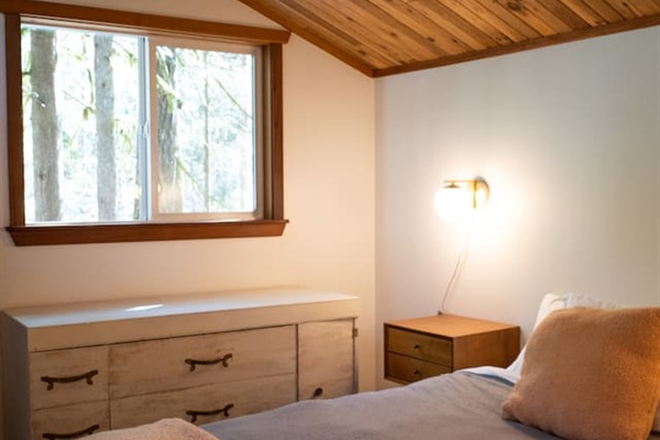 Master bedroom has a Queen bed, two nightstands with lights, a dresser, a closet, and an elevated forest view.  