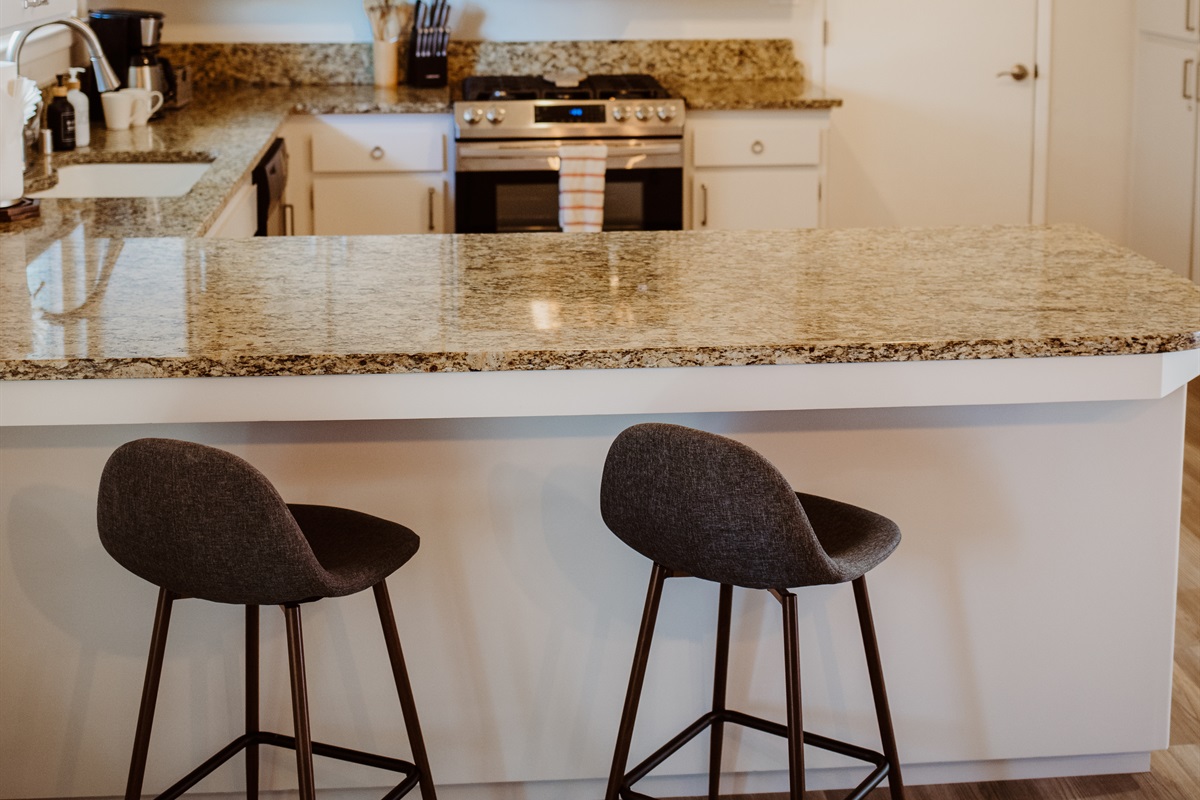 Enjoy a morning espresso at the sleek granite breakfast bar in this bright, modern kitchen.