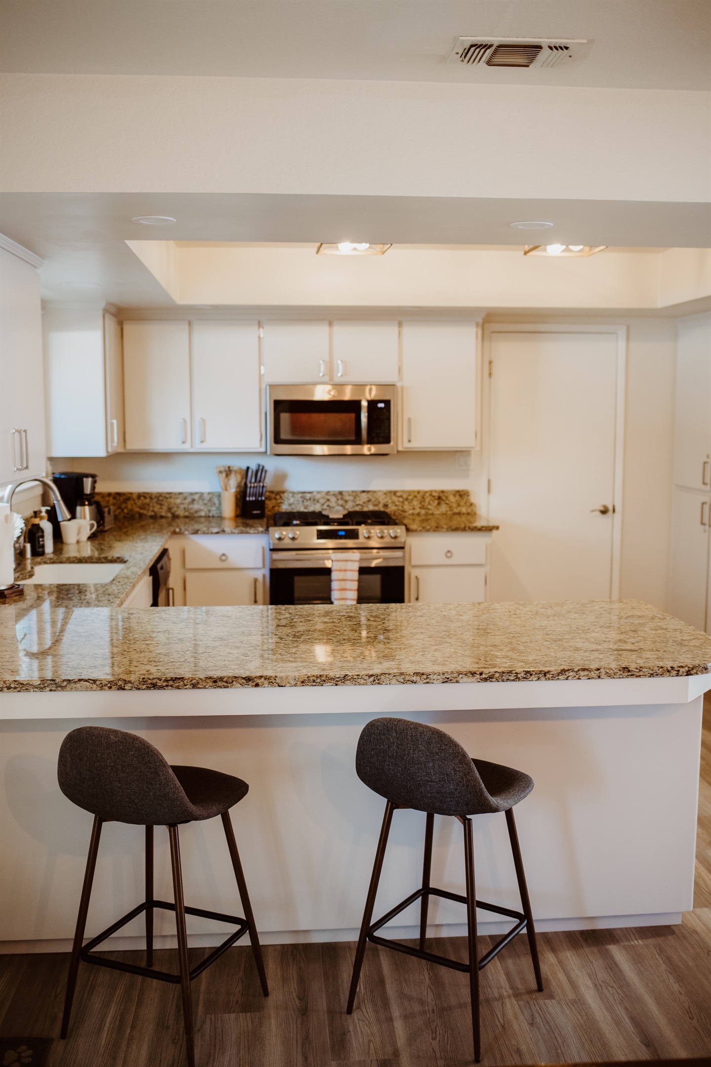 Enjoy a morning espresso at the sleek granite breakfast bar in this bright, modern kitchen.