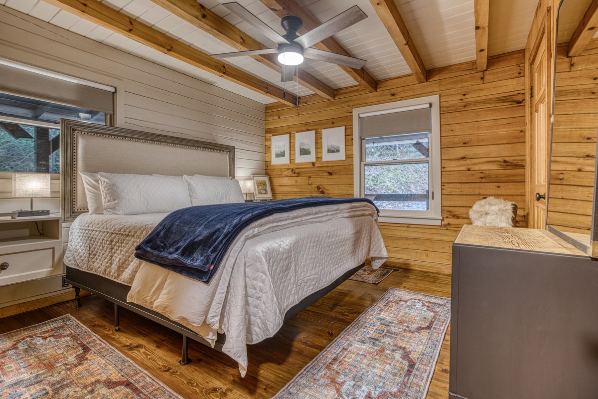 Bedroom with a navy throw and a ceiling fan.