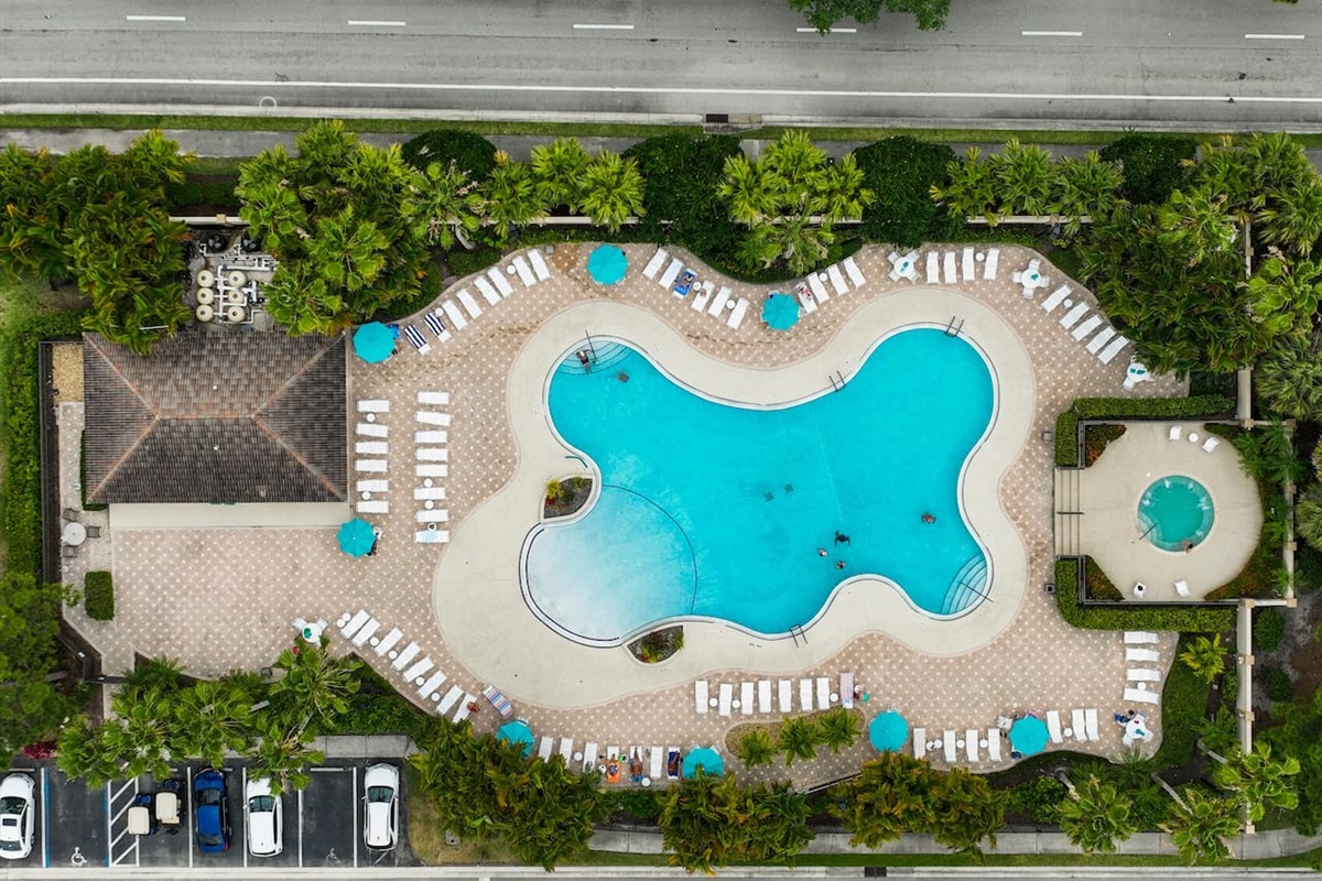 Aerial view of the resort-style community pool and spa with lounge seating and tropical surroundings.