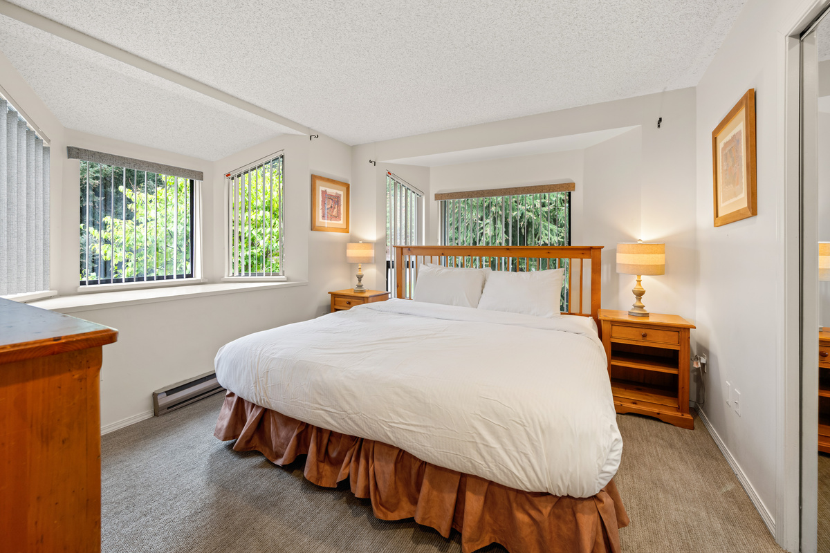 Primary bedroom with a queen bed, white bedding, matching night tables and bright windows behind the headboard on the 2nd floor.