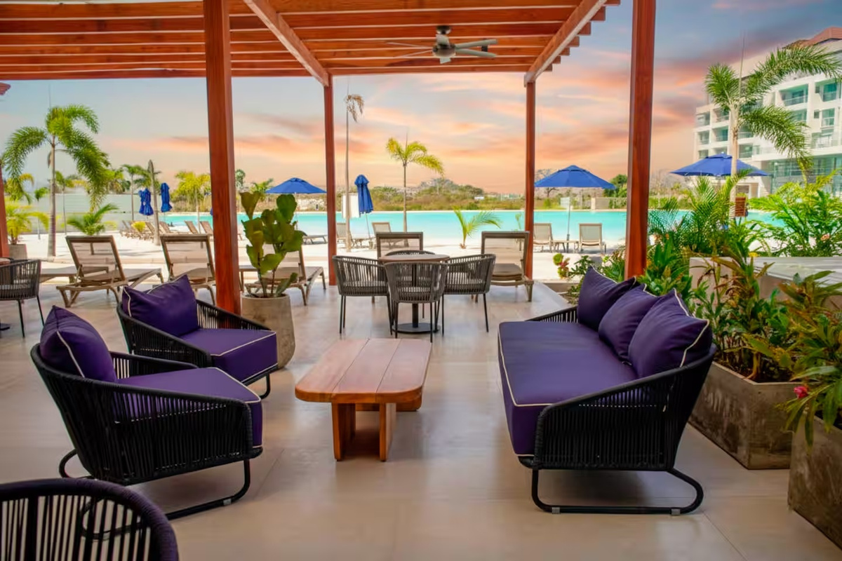 Zona lounge cubierta tipo resort junto a la piscina de la laguna, con asientos a la sombra y un entorno tropical para disfrutar de momentos de descanso junto a la costa.
