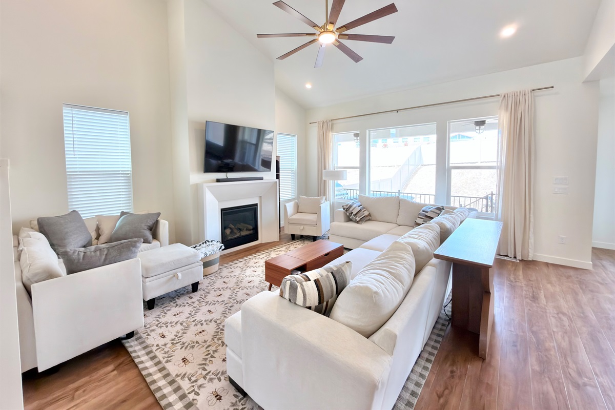 Bright and spacious main-level living room with vaulted ceilings, fireplace, and large Smart TV — perfect for family gatherings.