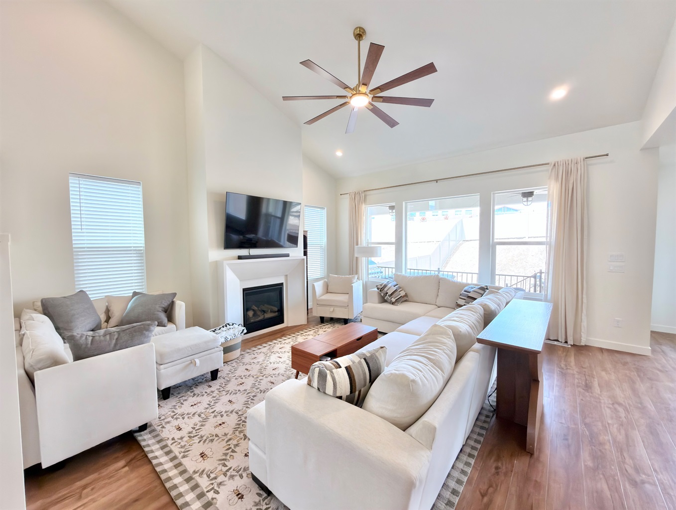 Bright and spacious main-level living room with vaulted ceilings, fireplace, and large Smart TV — perfect for family gatherings.