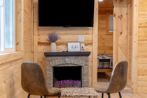 Sunlight fills this cozy corner, highlighting juniper pines and the firepit. With a warm fireplace, a big 55-inch TV, and chic seating, it’s the perfect spot to kick back, sip your coffee, and debate whether to explore or just lounge all day!