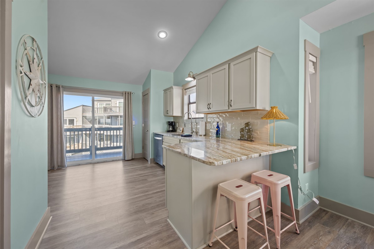 Bright coastal kitchen featuring a breakfast bar with seating and easy access to the balcony&mdash;perfect for quick meals and morning coffee