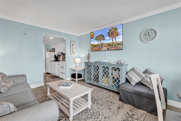 Full living room view with flat-screen TV, sofa, loveseat, and decorative storage cabinet