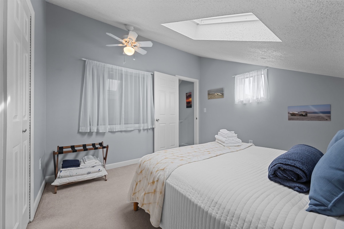 Another angle of the loft bedroom showcasing cozy finishes, fresh towels, and a peaceful coastal vibe