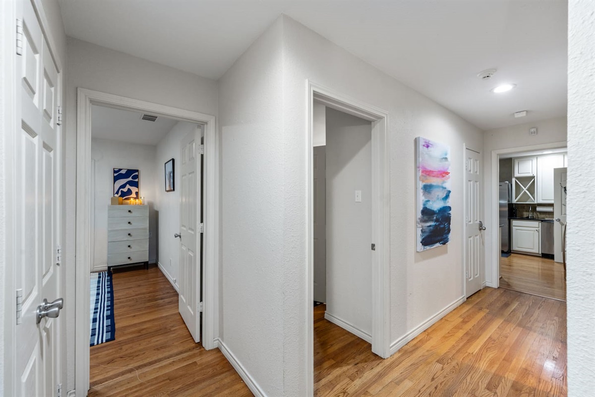 Spacious hallway with contemporary artwork and smooth transitions to bedrooms and the kitchen.
