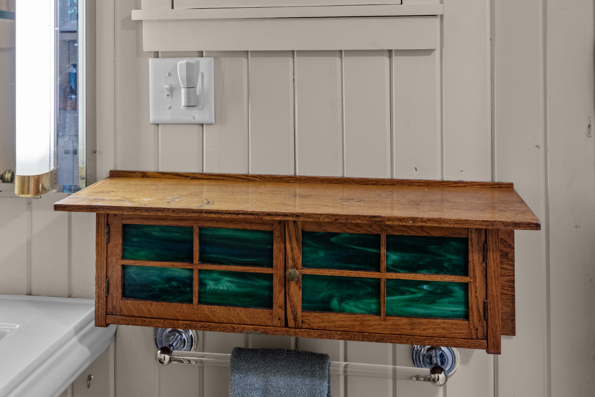Charming cottage details are found throughout the home, including this beautiful handcrafted cabinet that adds warmth and character to the bathroom.