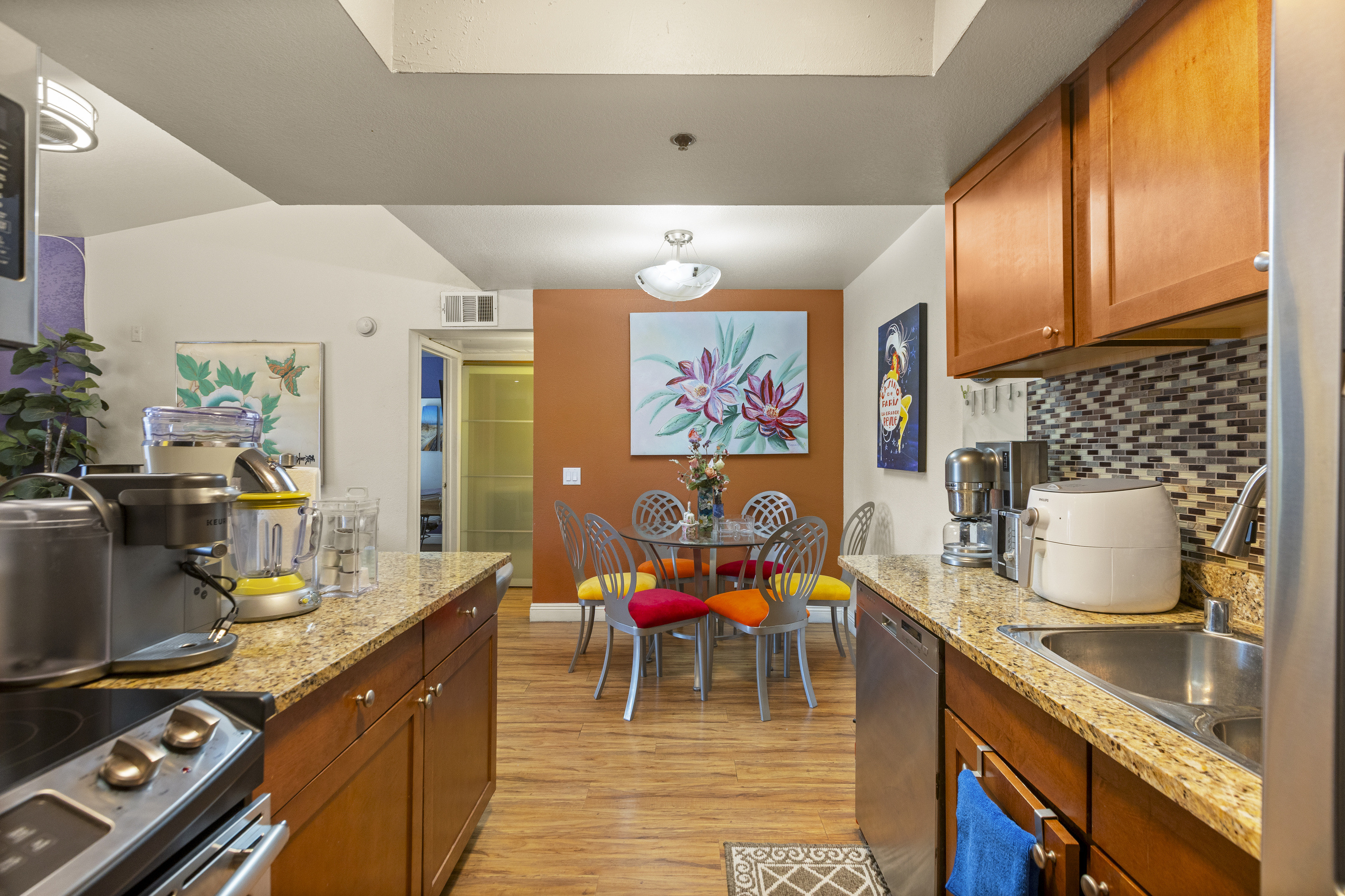 Kitchen with granite counters, wood cabinets, full appliances, and a round dining table just beyond the cooking area.
