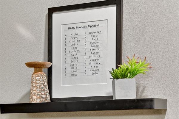 Unique wall shelf with framed décor and greenery. Small touches like this add charm and character to the modern design.