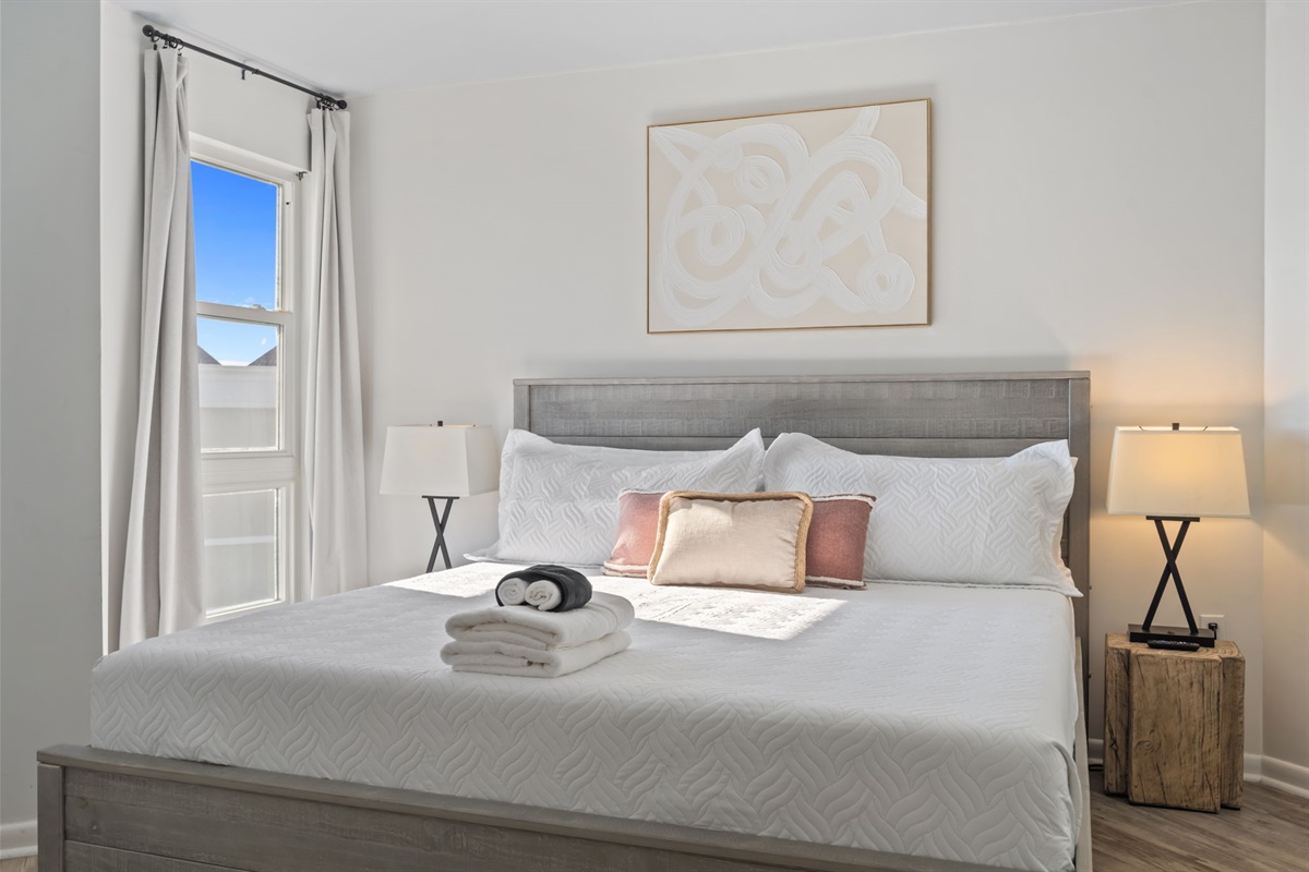 Bright and calming second bedroom with plush linens, soft coastal tones, and plenty of natural light