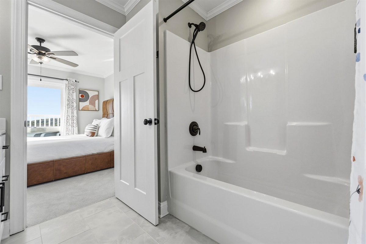 Relax in this bright coastal bedroom featuring a spa-style bathroom and direct access to the private balcony hot tub area
