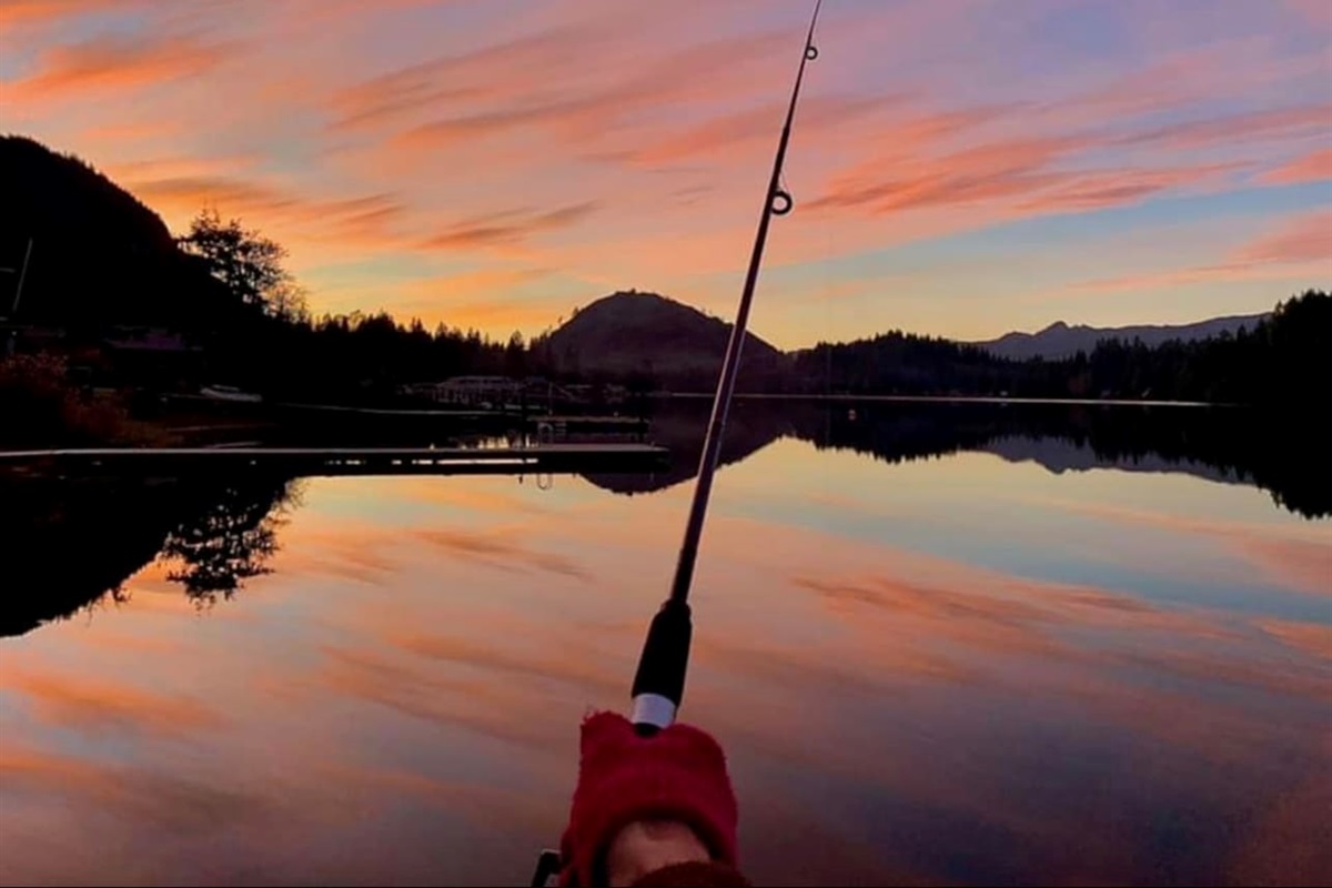 Fishing pole in hand with the lake glowing at sunset.