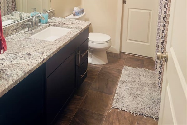 Modern bath with granite vanity, large mirror, and tiled shower.