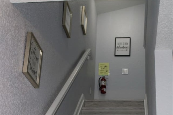 - Stairway with soft gray walls and motivational art for an inviting ascent  
- Wide steps and railing provide safety and ease for all guests  
- Leads to cozy upstairs bedrooms and additional living spaces  
