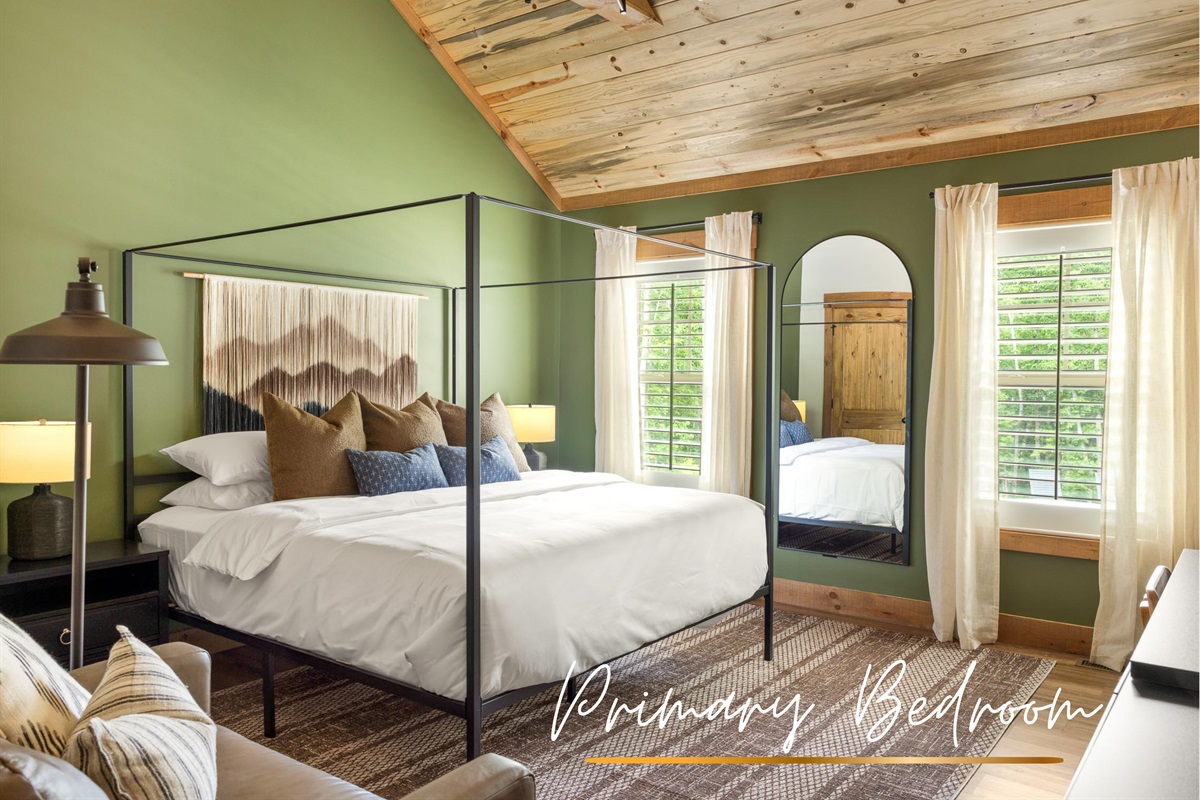 Soft green walls, plush white bedding, and neutral textures create a king suite that feels both elevated and deeply calming.