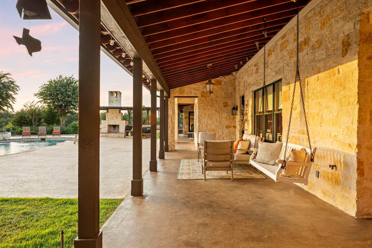A tranquil hanging chair inviting relaxation on a spacious stone patio, perfect for enjoying the outdoors.