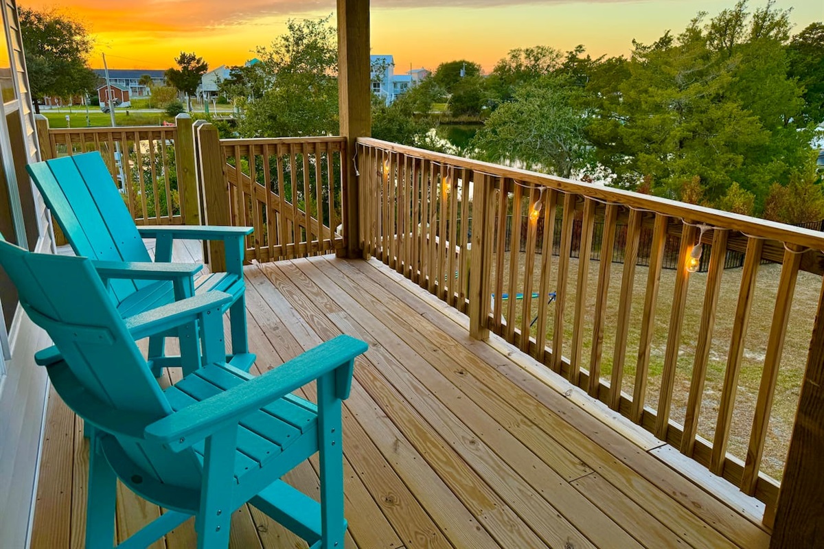 Private backyard dock with boat lift and fillet table, fenced-in backyard, fire pit with Adirondack chairs, hammocks, propane grill, picnic table, outdoor shower, expansive waterfront back deck with string lights, neighborhood boat ramp